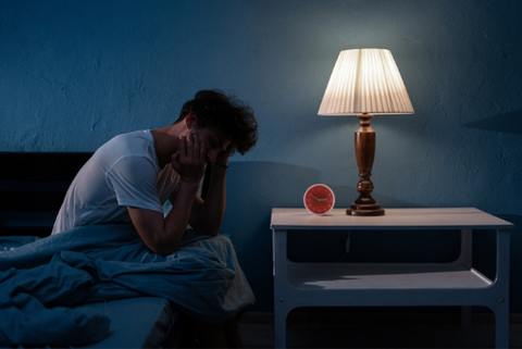 Person sitting in bed unable to sleep due to a sleep disorder like insomnia